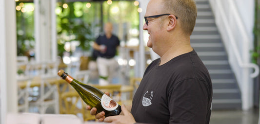Geoff Thompson holding a bottle of Grounded Cru Sparkling